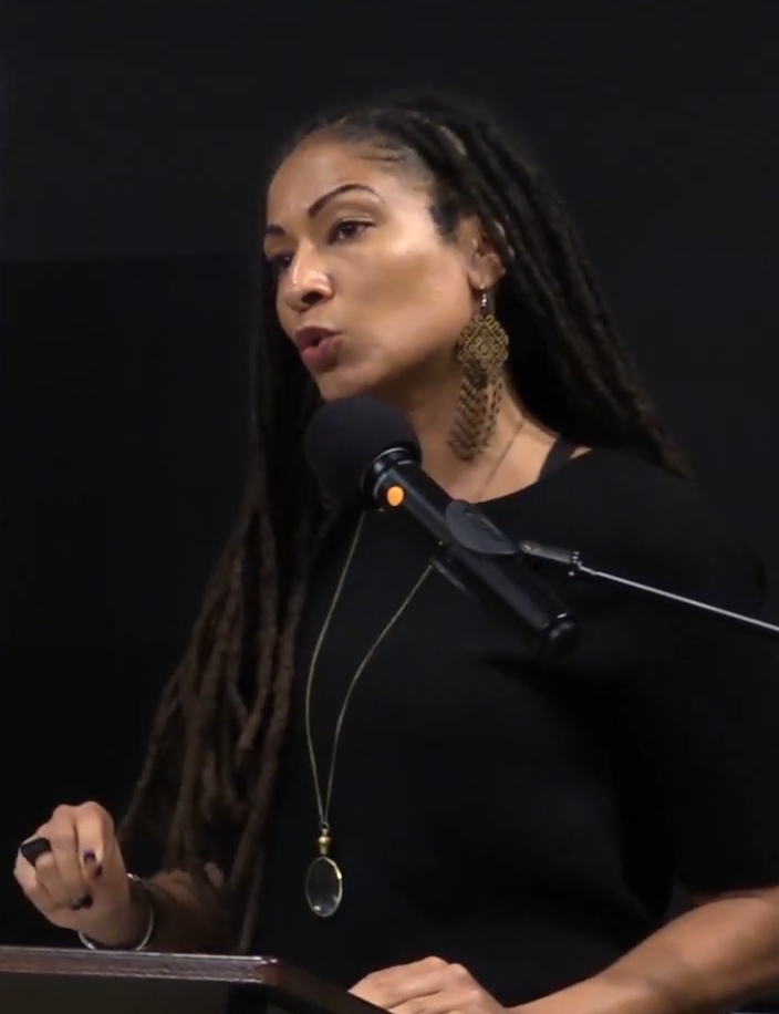 Photograph of Ruha Benjamin speaking at a podium
