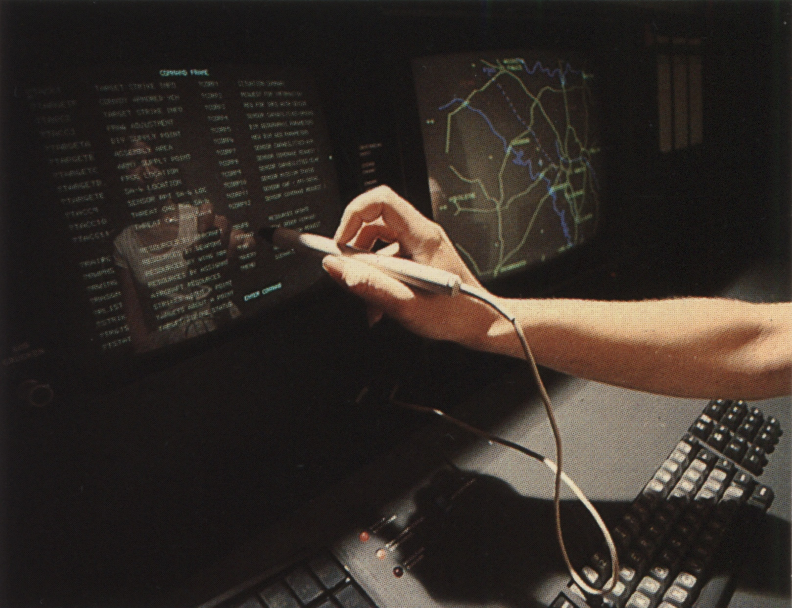 A person operating an IBM 3270 computer terminal with a light pen, around 1980